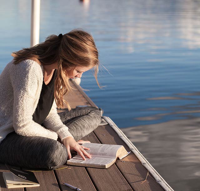 Woman reading her Bible on a dock