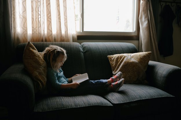 Little girl reading on a couch