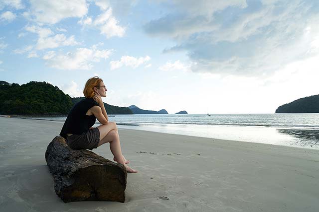 Woman sitting on rock looking over sea thinking about El-Elyon