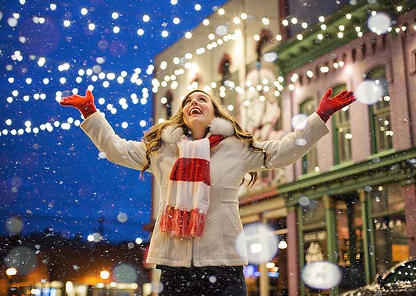 Woman in coat under snow and lights