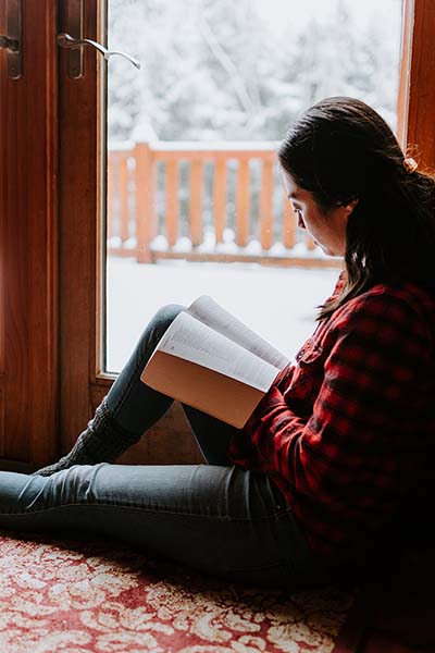 Woman reading Bible by window